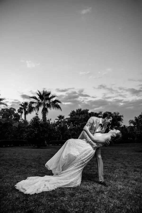 Groom dipping bride kiss under palm trees black and white - photographer marrakech